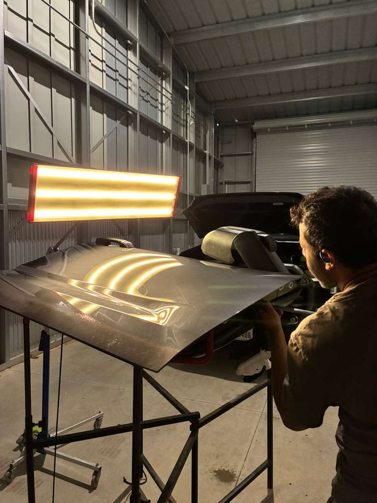 PDR specialist removing hail dents from vehicle hood under reflection lighting at SC Auto Hail Repair Madison